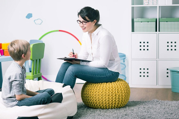 A woman sitting on top of a yellow ottoman.