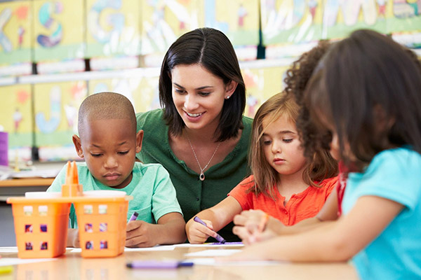 A woman is helping children with their writing.