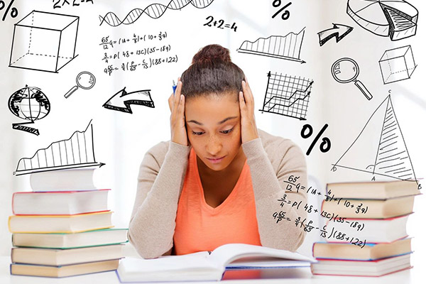 A girl is sitting at her desk with books and papers.