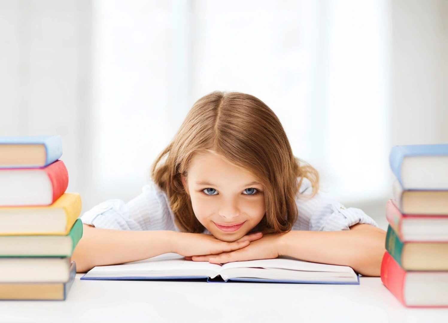 A little girl is laying on the table reading