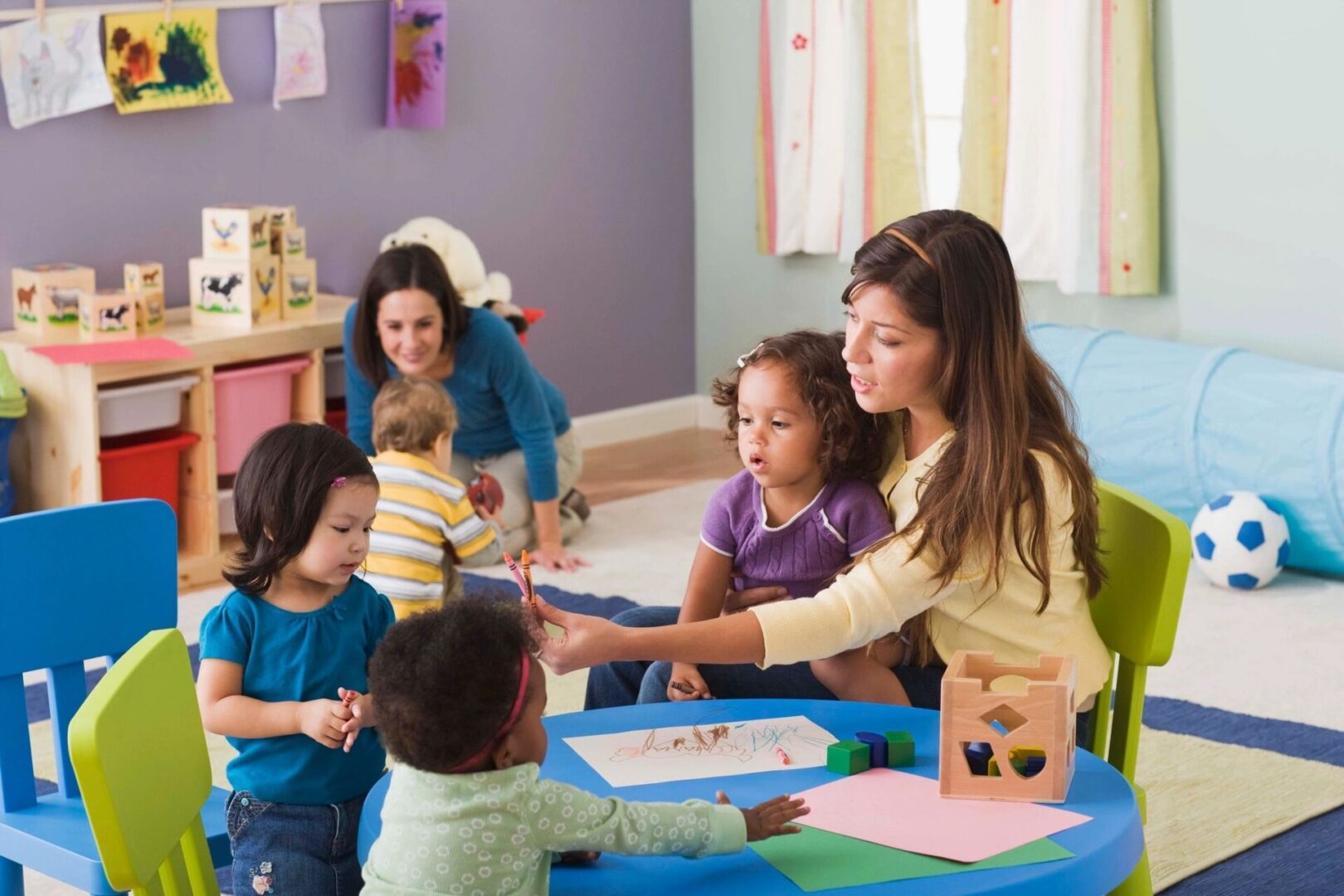 A woman is helping children with their crafts.