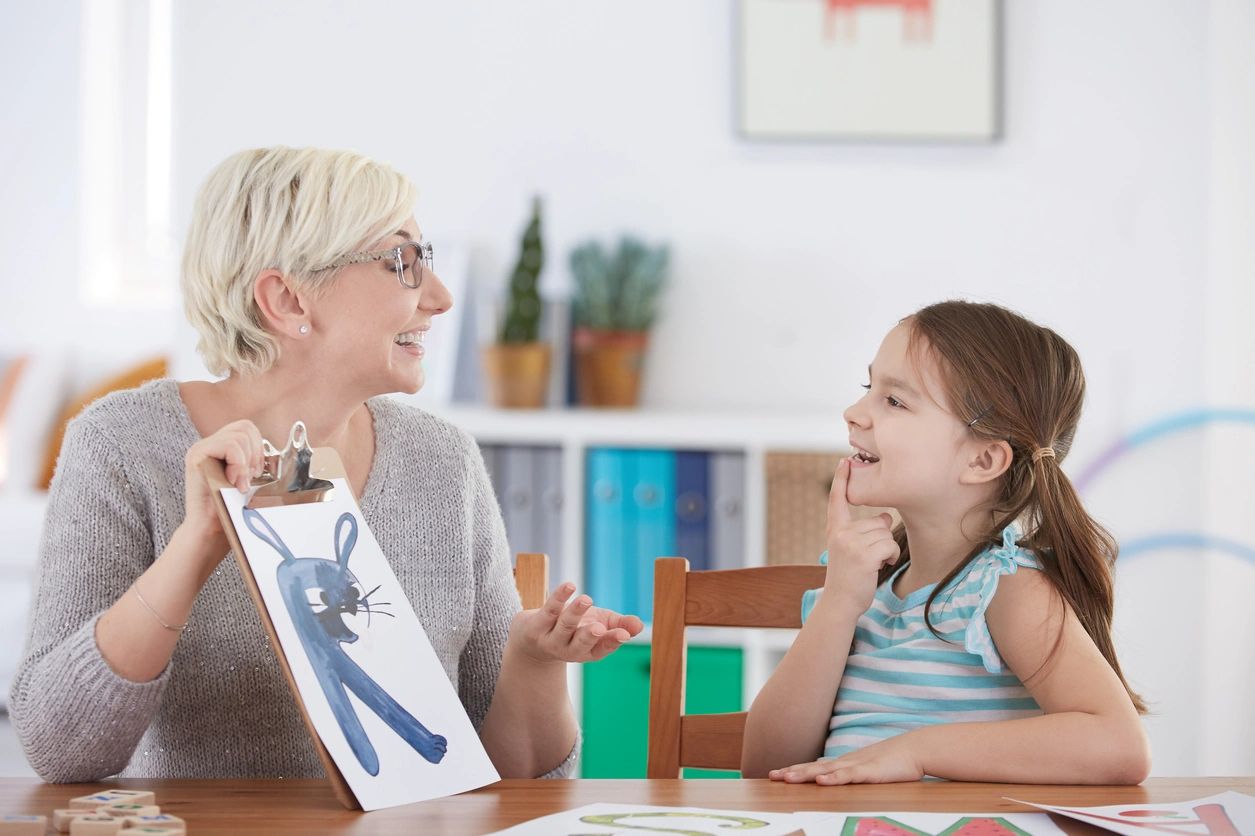 A woman and girl sitting at the table talking.