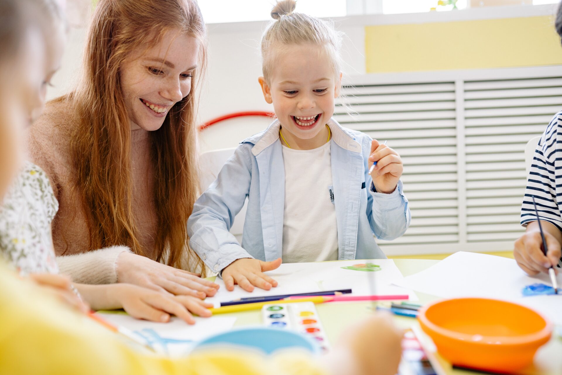 A woman and girl sitting at table with art supplies.